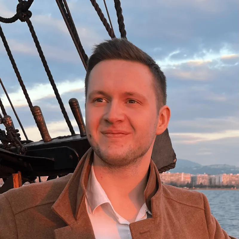 Victor Piekarski, founder of Farenson, beside the rigging of a moored sailing ship at sunset.